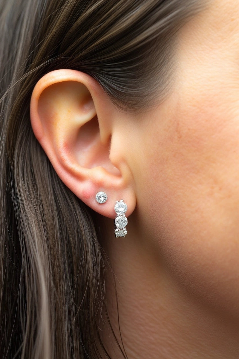 The model wears our Cushion Lab Grown Diamond Huggie Hoop Earrings by Adorn By You, featuring three sparkling lab-grown diamonds in each hoop. Available in 1, 2, and 3 carat options and crafted in 14K or 18K gold . The model is also wearing the studs which is also one of our classic collection 