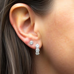 The model wears our Cushion Lab Grown Diamond Huggie Hoop Earrings by Adorn By You, featuring three sparkling lab-grown diamonds in each hoop. Available in 1, 2, and 3 carat options and crafted in 14K or 18K gold . The model is also wearing the studs which is also one of our classic collection 