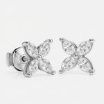 A pair of stud earrings in white gold features eight marquise-cut diamonds\u2014four per earring\u2014arranged symmetrically as a four-petal flower around a polished round center. Each diamond petal is secured by discreet prongs that emphasize the delicate floral motif. They sit side by side against a seamless white background under bright, even studio lighting that accentuates the metal\u2019s sheen and the stones\u2019 brilliance in a clean, high-key photographic style.