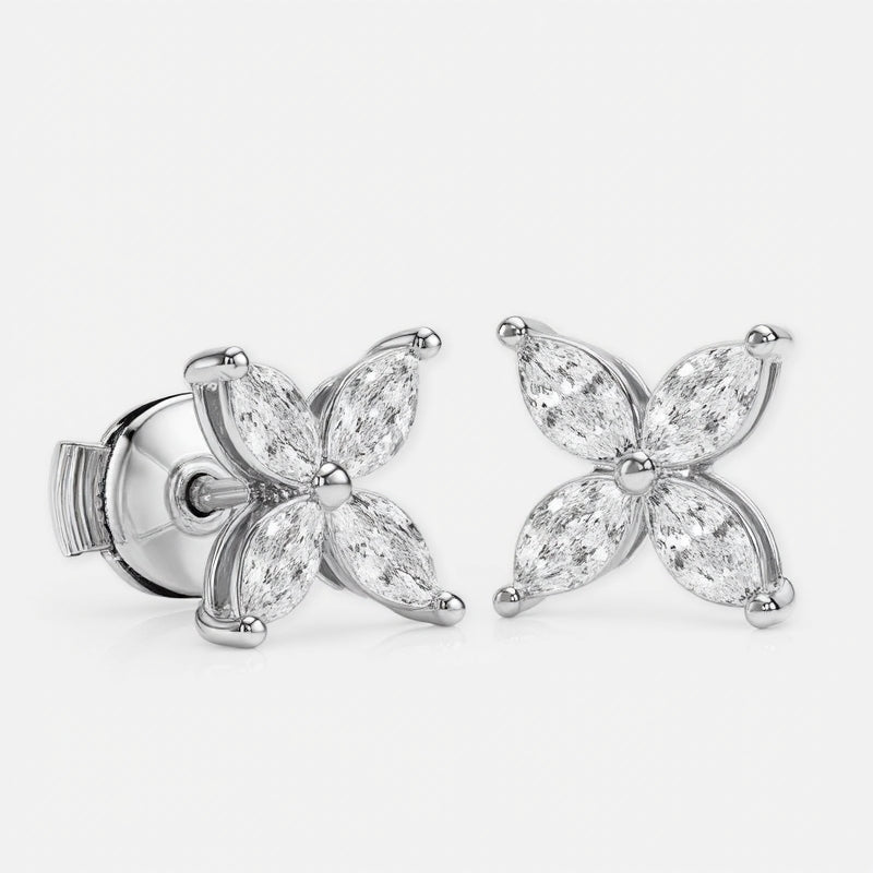 A pair of stud earrings in white gold features eight marquise-cut diamonds\u2014four per earring\u2014arranged symmetrically as a four-petal flower around a polished round center. Each diamond petal is secured by discreet prongs that emphasize the delicate floral motif. They sit side by side against a seamless white background under bright, even studio lighting that accentuates the metal\u2019s sheen and the stones\u2019 brilliance in a clean, high-key photographic style.