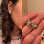 A single gold stud earring featuring four marquise-cut clear gemstones arranged in a cross shape is set in yellow gold. It is worn on the model\u2019s left earlobe and displayed in a tight profile headshot with dark hair pulled back. Soft, even lighting accentuates the sparkle of the stones against the wearer\u2019s smooth skin and white collar. The neutral background and crisp focus give the image a minimalist, editorial feel. | Adorn By You